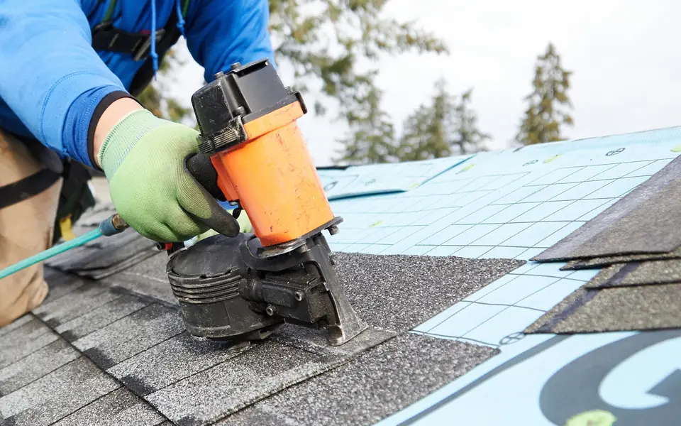 New asphalt shingles being nailed onto a roof deck